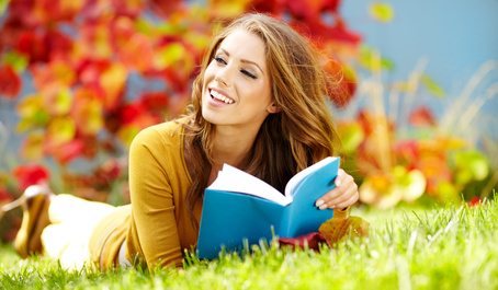 Portrait of a gorgeous brunette woman reading a book in the autumn park.